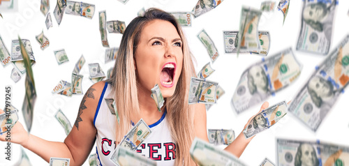 Young beautiful blonde woman wearing cheerleader uniform crazy and mad shouting and yelling with aggressive expression and arms raised. frustration concept. photo