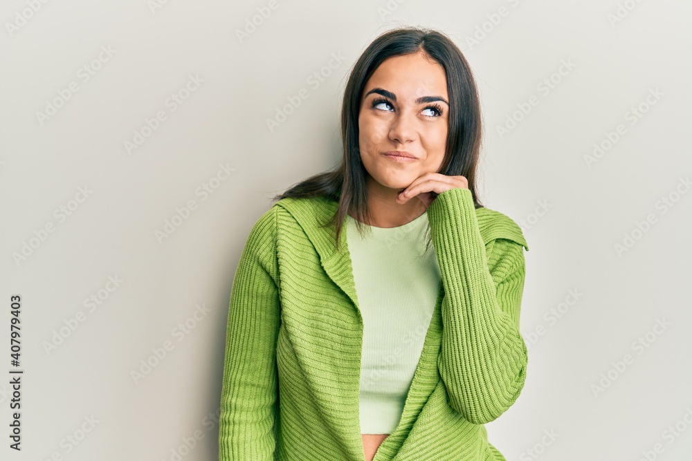 Young brunette woman wearing casual clothes with hand on chin thinking about question, pensive expression. smiling and thoughtful face. doubt concept. Young brunette woman wearing casual clothes with hand on chin thinking about question, pensive expression. smiling and thoughtful face. doubt concept.