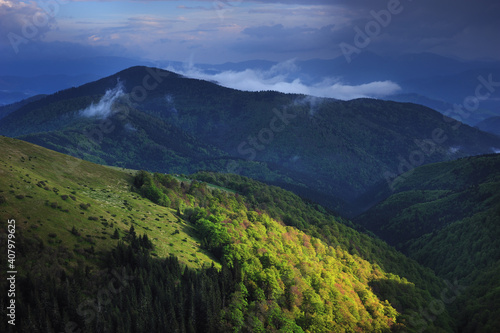 Panoramic view of a mountain range in the fog in cloudy summer weather at sunset. © Myshkovskyi