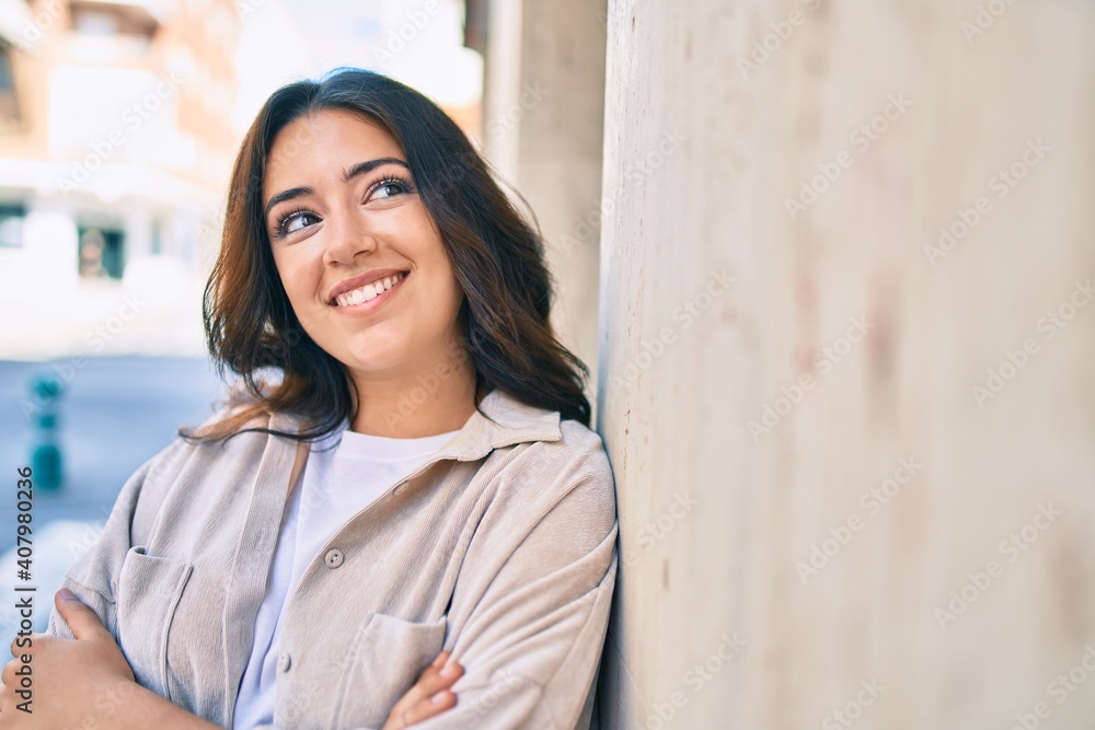 Young hispanic woman smiling happy leaning on the wall at the city. Young hispanic woman smiling happy leaning on the wall at the city.