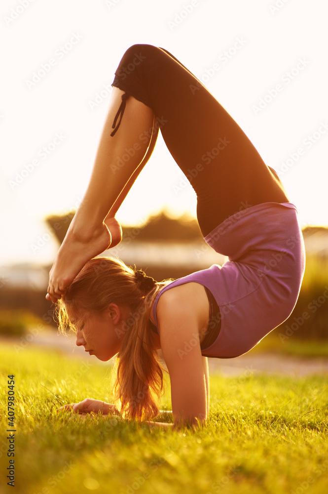 Young blonde woman practicing yoga in the park at sunset