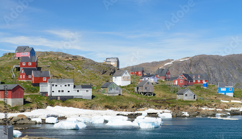 Greenland village with colorful homes on the water with icebergs.