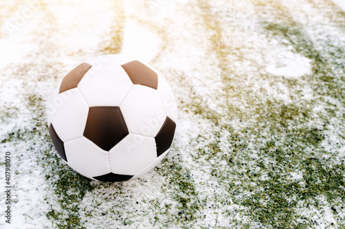 Soccer ball placed on snowy grass in winter on sports ground  copy space