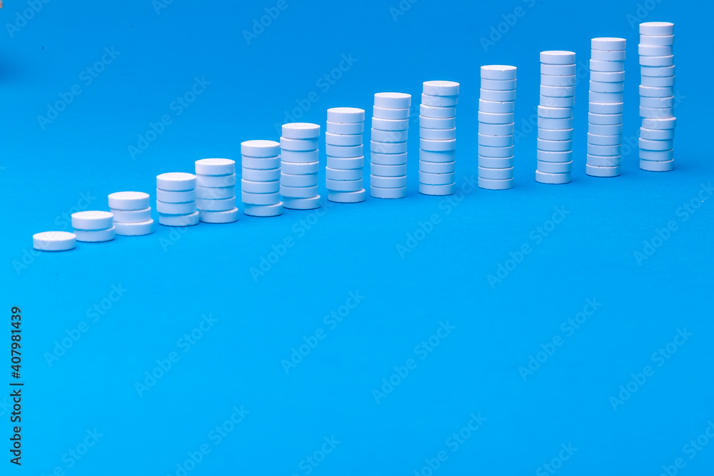 Close up pyramid concept of white pills on blue background with copy space. Focus on foreground, soft bokeh. Pharmacy drugstore concept. Close up pyramid concept of white pills on blue background with copy space. Focus on foreground, soft bokeh. Pharmacy drugstore concept.