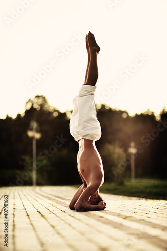 Young caucasian brunette man doing yoga in the park at sunset.