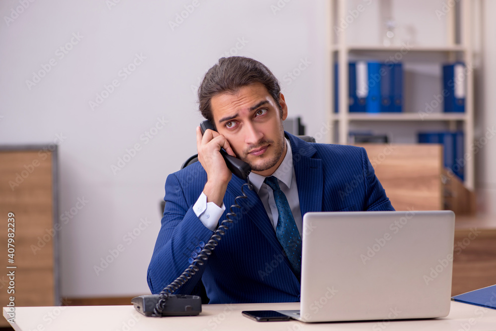 Young male employee unhappy with excessive work in the office Young male employee unhappy with excessive work in the office