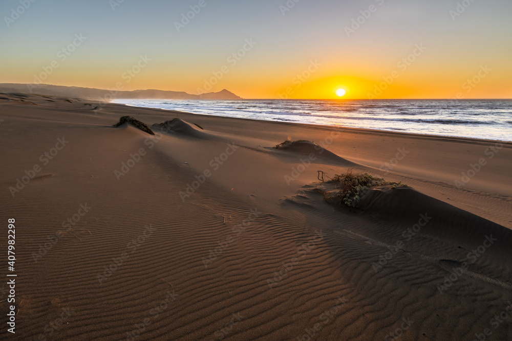 An amazing sea view during sunset time of an awe sandy beach full of sand dunes till the infinite. Idyllic natural landscape for going back to nature and enjoy the outdoors again