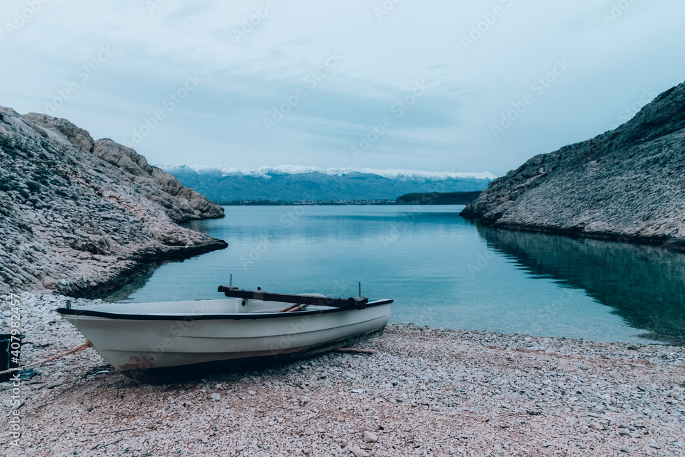 Boat on the beach and snowy peaks of Velebit mountains on the background, Nin, Croatia.