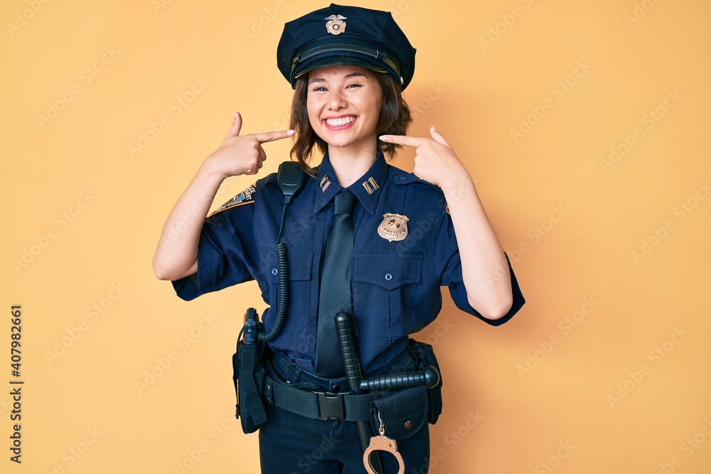Young beautiful woman wearing police uniform smiling cheerful showing and pointing with fingers teeth and mouth. dental health concept. Young beautiful woman wearing police uniform smiling cheerful showing and pointing with fingers teeth and mouth. dental health concept.