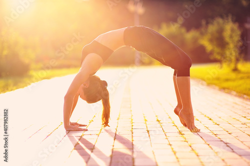 Young caucasian woman practicing yoga at sunset in the park. A woman is resting in a summer park and doing yoga.