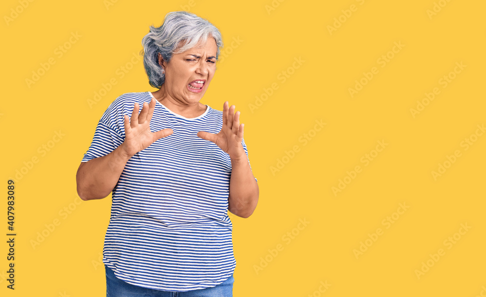 Senior woman with gray hair wearing casual striped clothes disgusted expression, displeased and fearful doing disgust face because aversion reaction. with hands raised Senior woman with gray hair wearing casual striped clothes disgusted expression, displeased and fearful doing disgust face because aversion reaction. with hands raised