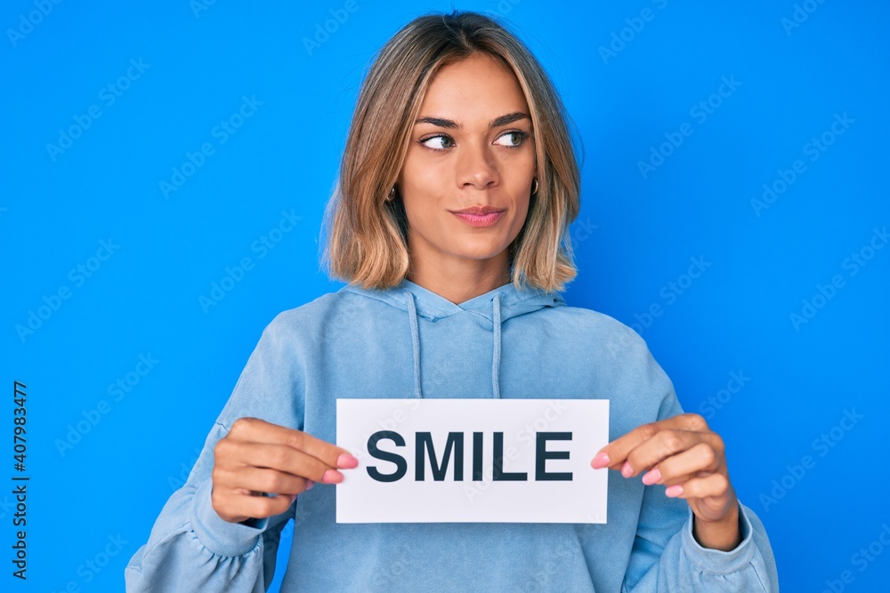 Beautiful caucasian woman holding smile text smiling looking to the side and staring away thinking. Beautiful caucasian woman holding smile text smiling looking to the side and staring away thinking.