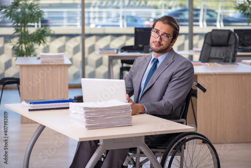 Young male employee in wheel-chair working in the office © Elnur