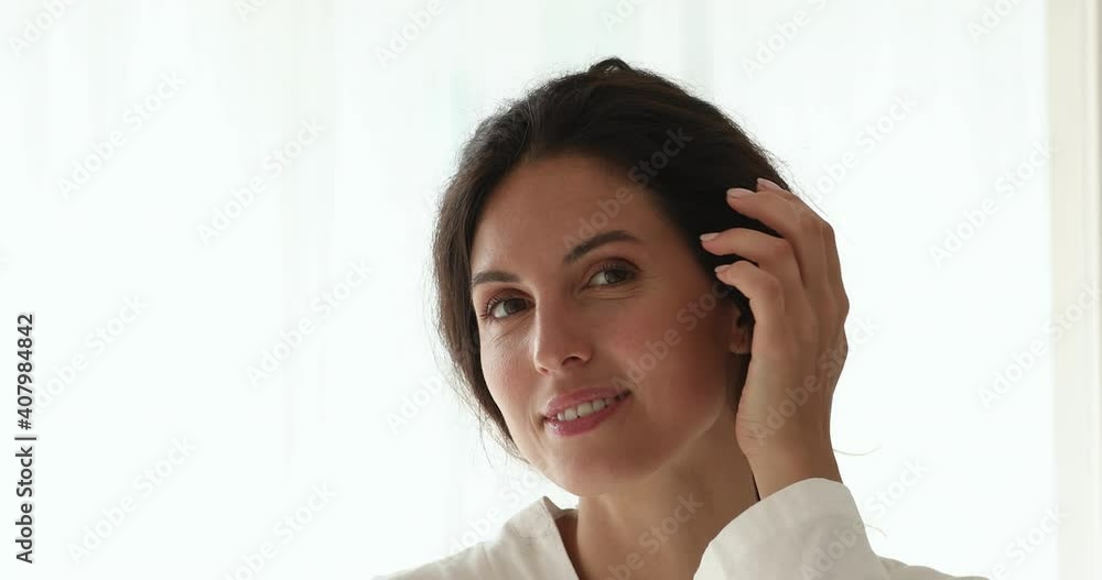 Close up head shot emotional positive smiling young pretty european woman looking at camera, making facial massage, touching hydrated skin, satisfied with freshness, enjoying spa procedure results. Close up head shot emotional positive smiling young pretty european woman looking at camera, making facial massage, touching hydrated skin, satisfied with freshness, enjoying spa procedure results.