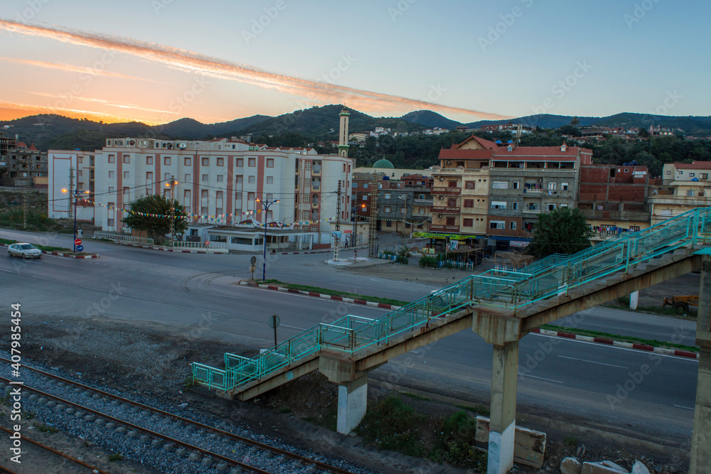 Pedestrian bridge over the highway near the residences and the railway at sunrise, the pedestrian bridge
