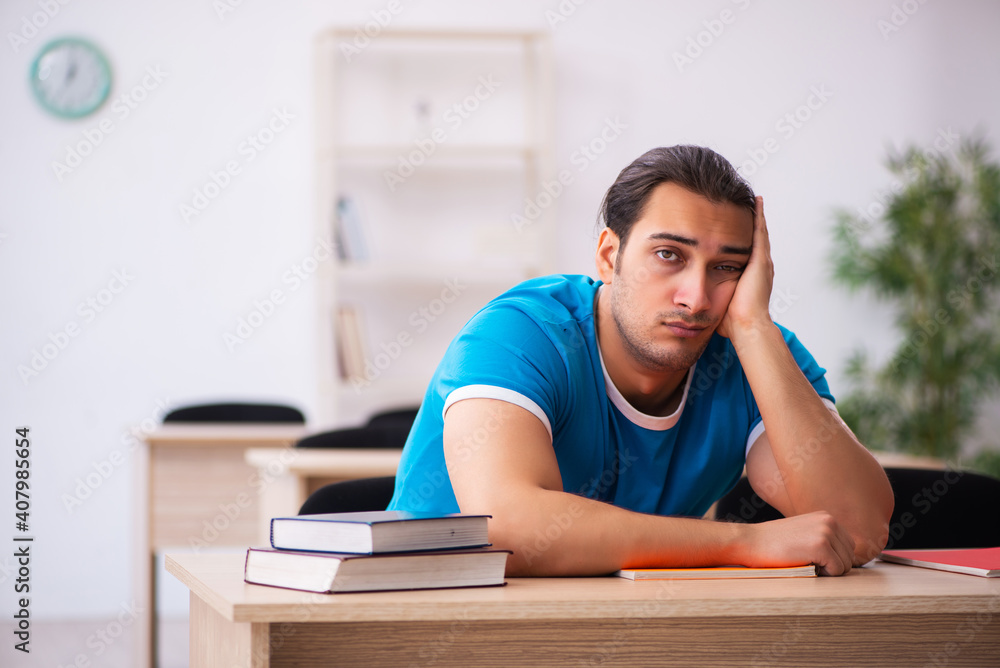 Exhausted male student preparing for the exams in the classroom Exhausted male student preparing for the exams in the classroom