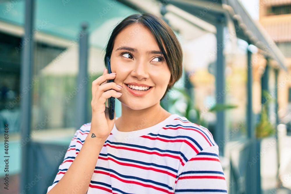 Young latin girl smiling happy talking on the smartphone at the city