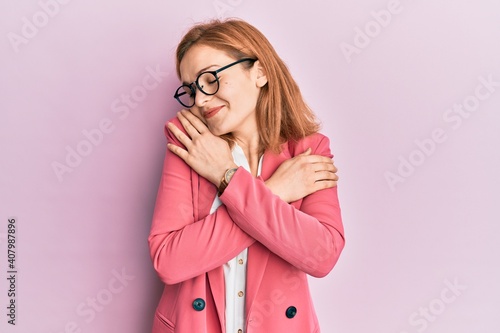Quadro em tela Young caucasian woman wearing business style and glasses hugging oneself happy and positive, smiling confident