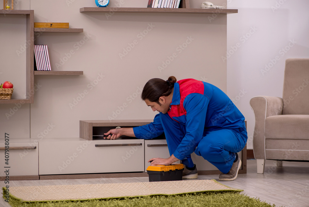 Young male contractor repairing drawyer indoors Young male contractor repairing drawyer indoors