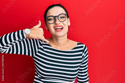 Young caucasian woman wearing casual clothes and glasses smiling doing phone gesture with hand and fingers like talking on the telephone. communicating concepts.