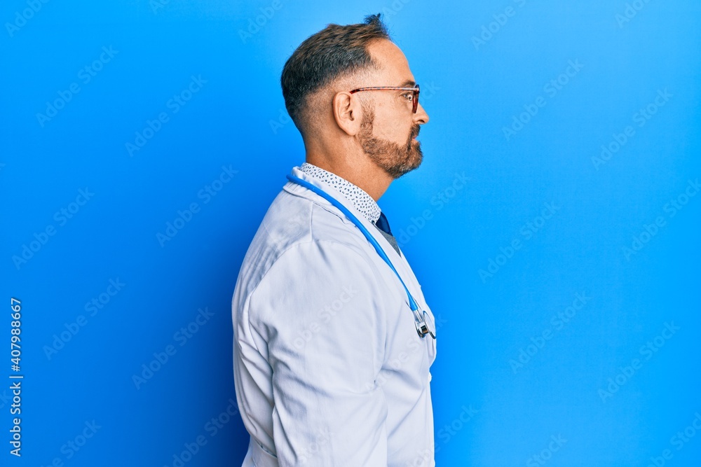 Handsome middle age man wearing doctor uniform and stethoscope looking to side, relax profile pose with natural face with confident smile. Handsome middle age man wearing doctor uniform and stethoscope looking to side, relax profile pose with natural face with confident smile.