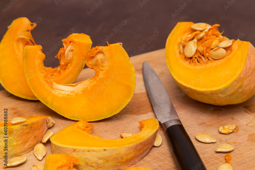 Cutting pumpkin wedges on wooden board. Cooking healthy vegetarian food at home
