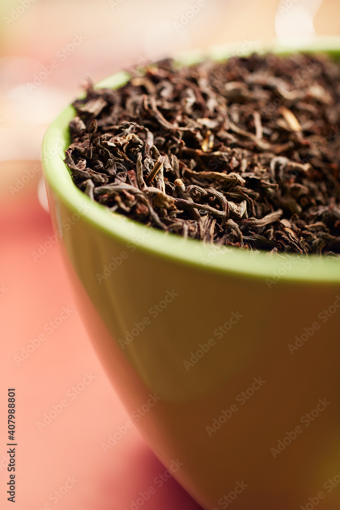 Closeup of dried black tea leaves in a green cup on a table Closeup of dried black tea leaves in a green cup on a table