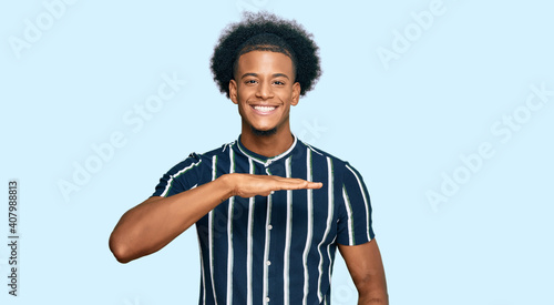 African american man with afro hair wearing casual clothes gesturing with hands showing big and large size sign, measure symbol. smiling looking at the camera. measuring concept.