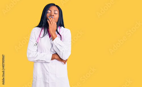 Young african american woman wearing doctor stethoscope bored yawning tired covering mouth with hand. restless and sleepiness.