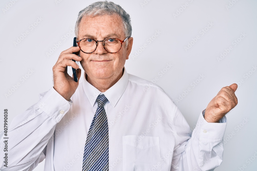 Senior grey-haired man wearing business clothes having conversation talking on the smartphone screaming proud, celebrating victory and success very excited with raised arm Senior grey-haired man wearing business clothes having conversation talking on the smartphone screaming proud, celebrating victory and success very excited with raised arm