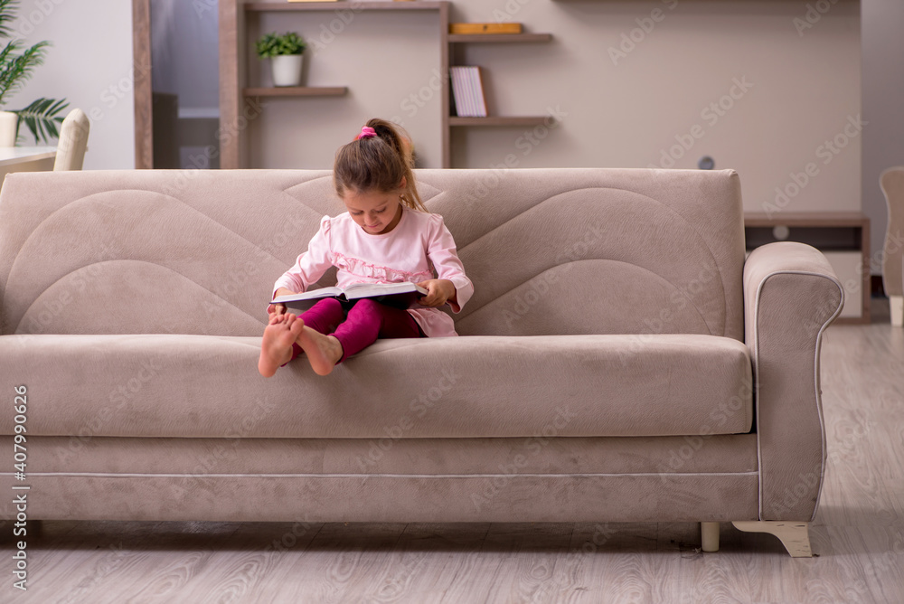 Small girl reading book at home