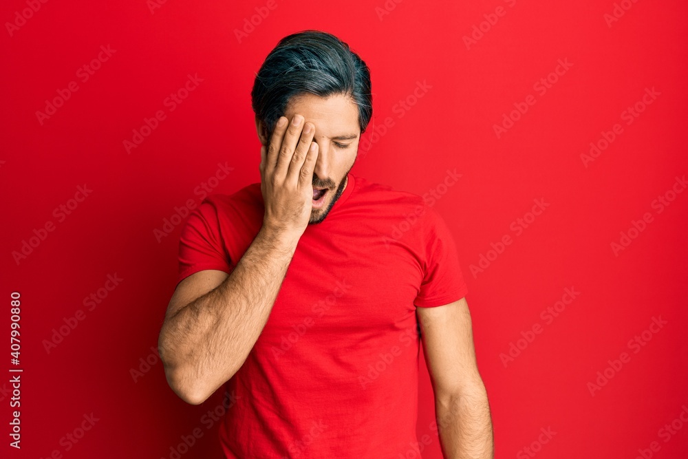 Young hispanic man wearing casual red t shirt yawning tired covering half face, eye and mouth with hand. face hurts in pain. Young hispanic man wearing casual red t shirt yawning tired covering half face, eye and mouth with hand. face hurts in pain.