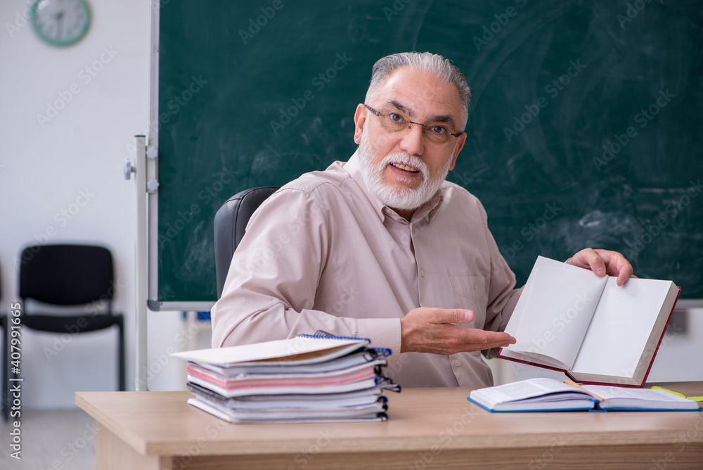Old male teacher sitting in the classroom Old male teacher sitting in the classroom