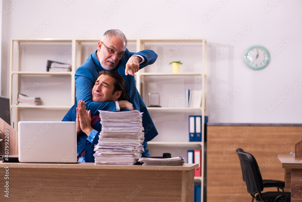 Old male boss and his young male assistant in bullying concept Old male boss and his young male assistant in bullying concept