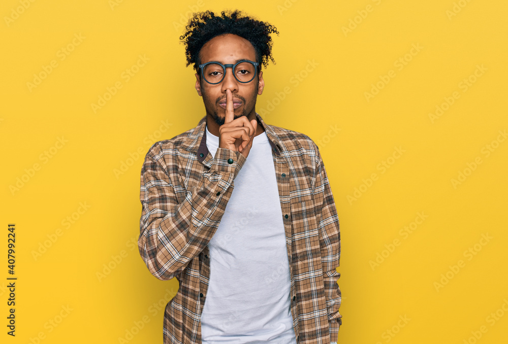 Young african american man with beard wearing casual clothes and glasses asking to be quiet with finger on lips. silence and secret concept. Young african american man with beard wearing casual clothes and glasses asking to be quiet with finger on lips. silence and secret concept.