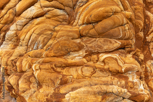 Closeup of the surface of the sandstone cliff face at Duvauchelle on the Banks Peninsula, Canterbury, New Zealand. The surface is highly coloured and textured.