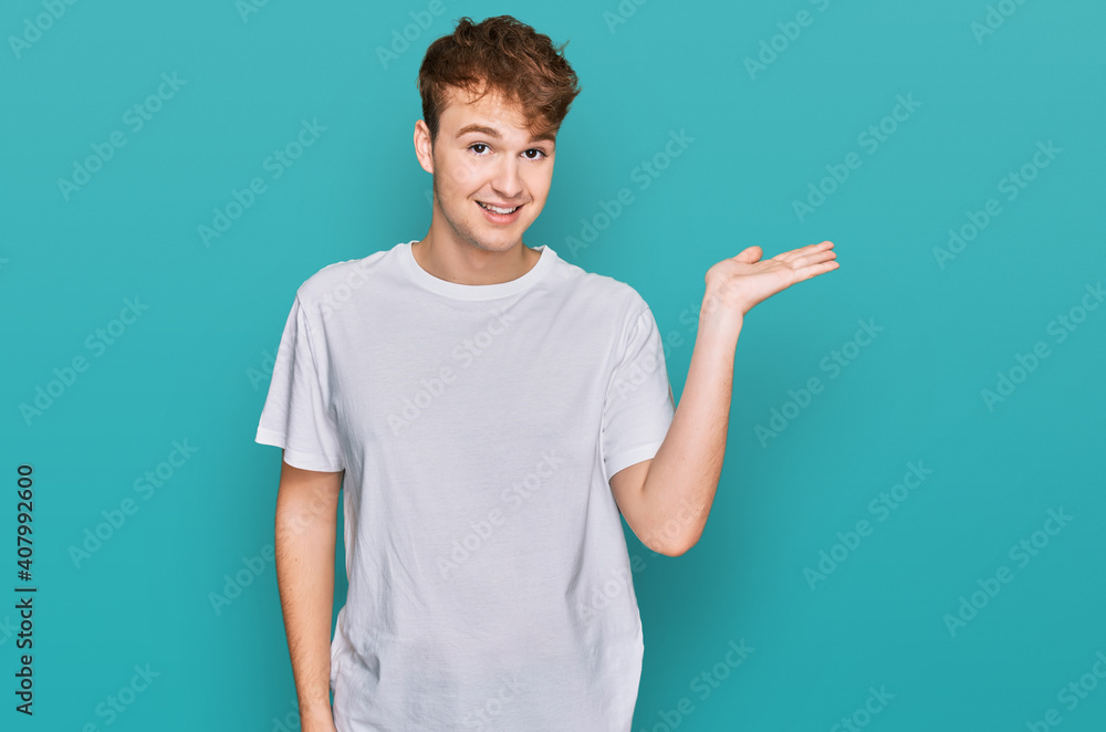 Young caucasian man wearing casual white t shirt smiling cheerful presenting and pointing with palm of hand looking at the camera. Young caucasian man wearing casual white t shirt smiling cheerful presenting and pointing with palm of hand looking at the camera.
