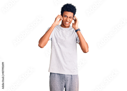 Young african american man wearing casual clothes covering ears with fingers with annoyed expression for the noise of loud music. deaf concept.