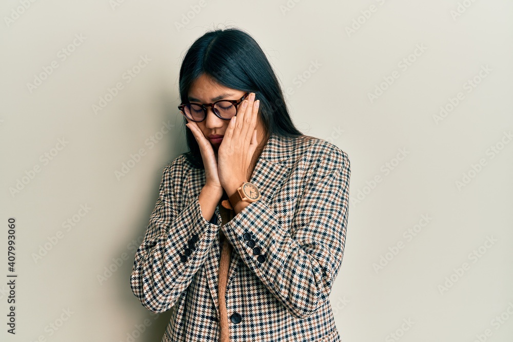 Young chinese woman wearing business style and glasses with sad expression covering face with hands while crying. depression concept. Young chinese woman wearing business style and glasses with sad expression covering face with hands while crying. depression concept.