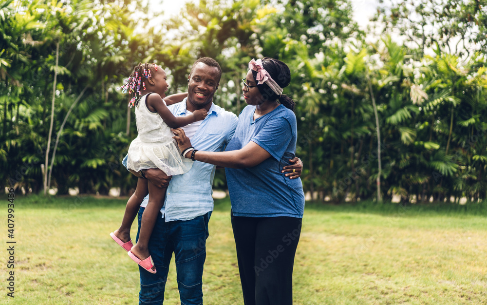 Fototapeta premium Portrait of enjoy happy love black family african american father and mother with little african girl child smiling and play having fun moments good time in summer park at home