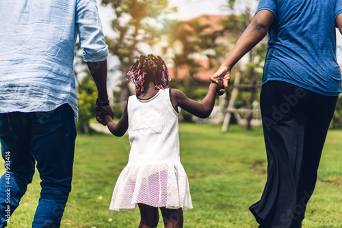 Portrait of enjoy happy love black family african american father and mother holding little african girl hand in moments good time in summer park at home