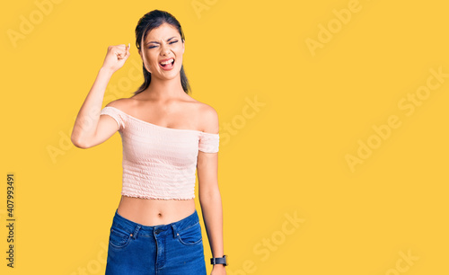 Young beautiful woman wearing casual clothes angry and mad raising fist frustrated and furious while shouting with anger. rage and aggressive concept.