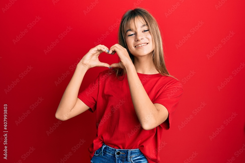 Teenager caucasian girl wearing casual red t shirt smiling in love doing heart symbol shape with hands. romantic concept. Teenager caucasian girl wearing casual red t shirt smiling in love doing heart symbol shape with hands. romantic concept.