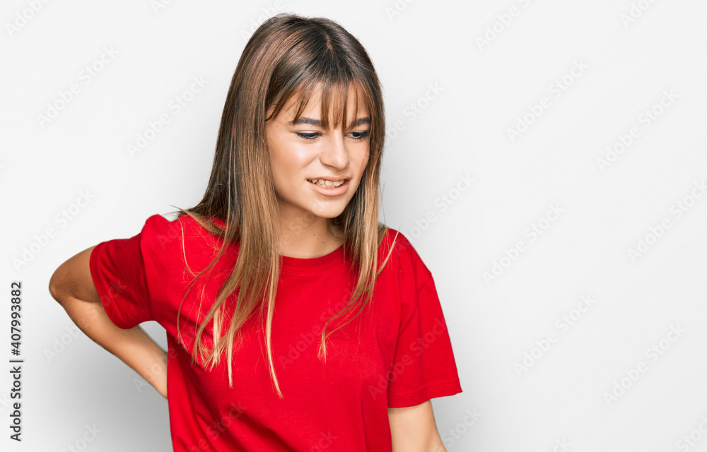 Teenager caucasian girl wearing casual red t shirt suffering of backache, touching back with hand, muscular pain Teenager caucasian girl wearing casual red t shirt suffering of backache, touching back with hand, muscular pain
