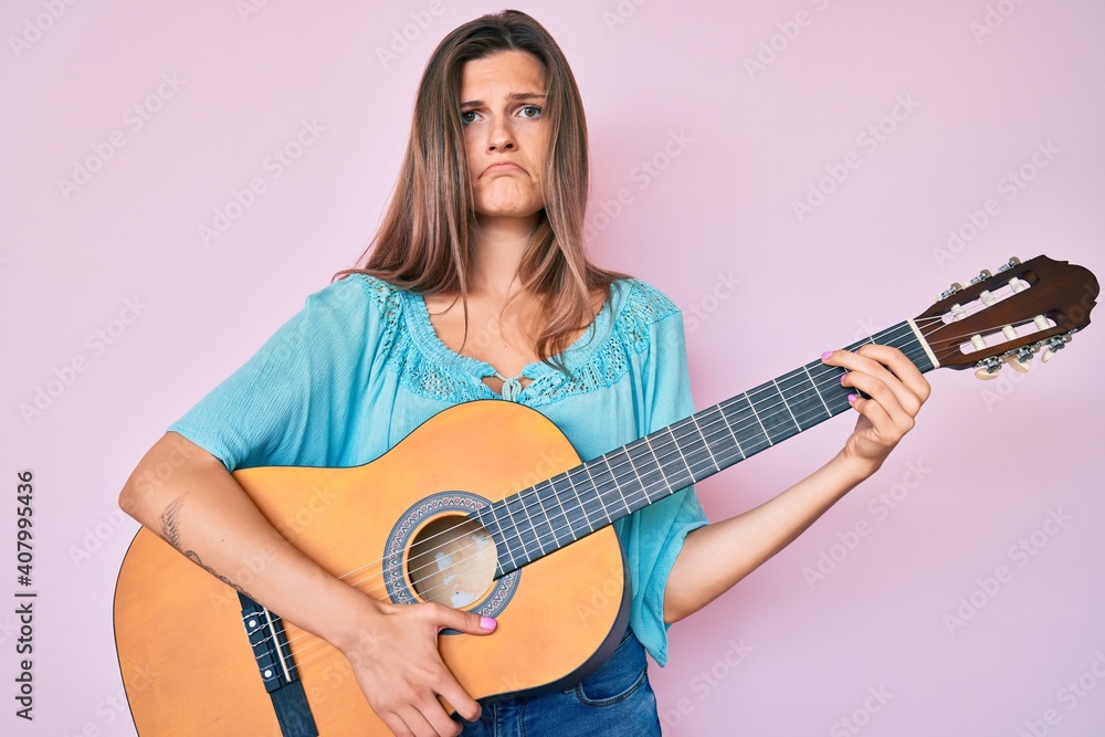 Beautiful caucasian woman playing classical guitar depressed and worry for distress, crying angry and afraid. sad expression. Beautiful caucasian woman playing classical guitar depressed and worry for distress, crying angry and afraid. sad expression.