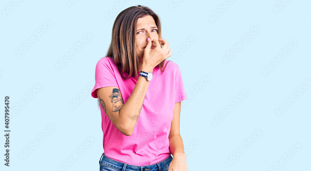 Beautiful caucasian woman wearing casual clothes smelling something stinky and disgusting, intolerable smell, holding breath with fingers on nose. bad smell Beautiful caucasian woman wearing casual clothes smelling something stinky and disgusting, intolerable smell, holding breath with fingers on nose. bad smell