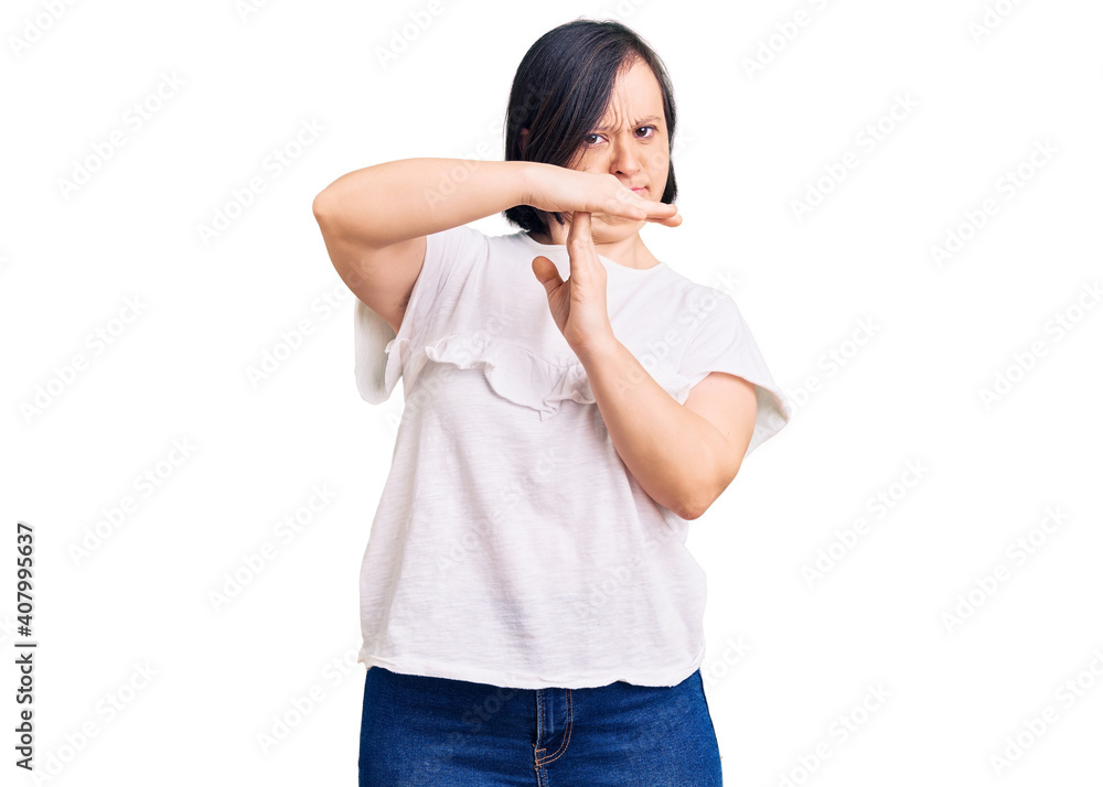 Brunette woman with down syndrome wearing casual white tshirt doing time out gesture with hands, frustrated and serious face Brunette woman with down syndrome wearing casual white tshirt doing time out gesture with hands, frustrated and serious face
