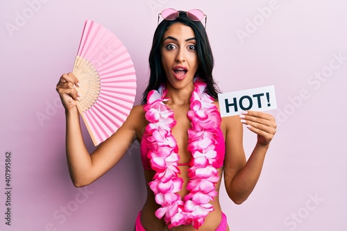 Beautiful hispanic woman wearing bikini and handfan holding hot word celebrating crazy and amazed for success with open eyes screaming excited. © Krakenimages.com