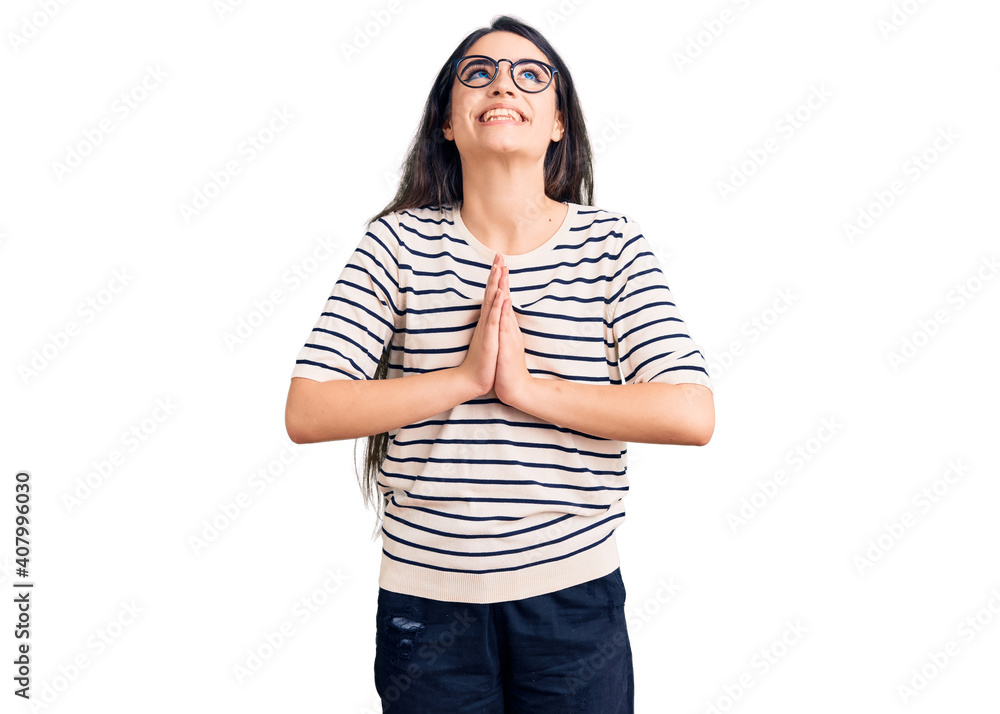 Brunette teenager girl wearing casual clothes and glasses begging and praying with hands together with hope expression on face very emotional and worried. begging. Brunette teenager girl wearing casual clothes and glasses begging and praying with hands together with hope expression on face very emotional and worried. begging.
