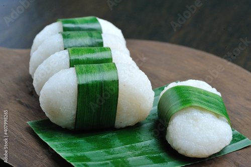 Jadah wrapped in banana leaves on a wooden cutting board. Jadah is a typical Indonesian food made from sticky rice photo